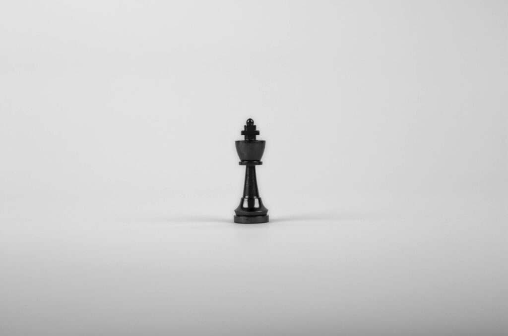 A minimalist black chess king piece on a white background, representing strategy and power.